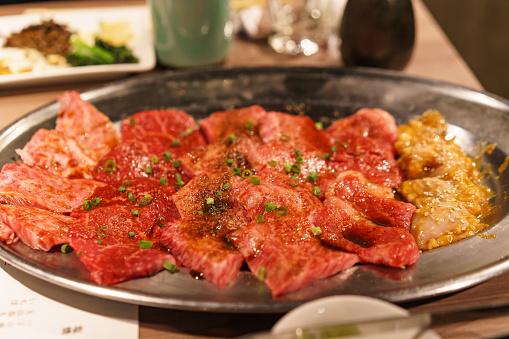 Yakiniku - Grilling meat at a yakiniku restaurant.\nAssorted raw meat before cooking the grilled meat.\nVarious parts of meat.