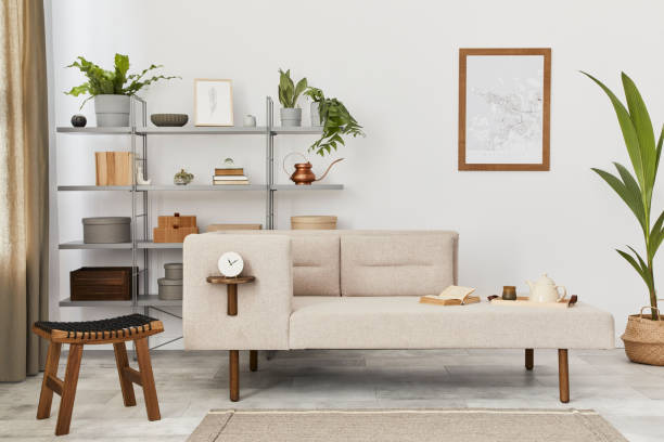 istock Cozy interior with stylish sofa, grey coffee table, bookcase, plants, carpet, decoration, mock up poster map and elegant personal accessories. Neutral living room in classic house. Template. 1288636070