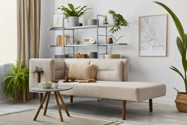 istock Cozy interior with stylish sofa, design coffee table, bookcase, plants, carpet, decoration, mock up poster map and elegant personal accessories. Neutral living room in classic house. Template. 1288636075