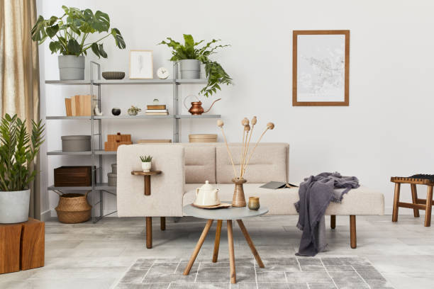 istock Cozy interior with stylish sofa, design coffee table, bookcase, plants, carpet, decoration, mock up poster map and elegant personal accessories. Neutral living room in classic house. Template. 1288636087
