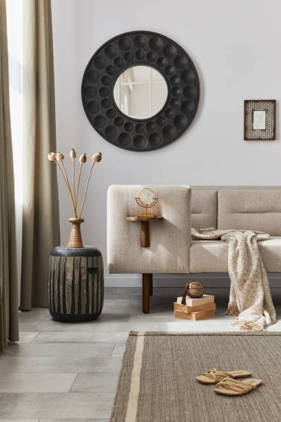 istock Interior design of ethnic style living room with modern commode, round mirror, decoration, furniture and personal accessories. Template. White wall. 1288636200