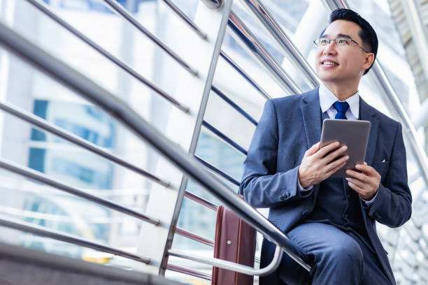 デジタルタブレットを持つハンサムなアジアのビジネスマンは、スーツと眼鏡を着用してください。リーダーシップエグゼクティブビジネスの男は、ビジネスの成功を得る。男性は自信を得� - asia businessman asian ethnicity happiness ストックフォトと画像