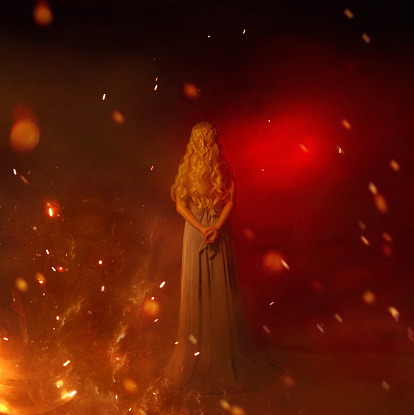 mistress of fire in red room full of flame and burning sparks, lady with long curled white blond hair in gray vintage dress, girl with hands behind her back, young woman with highlights and heat.