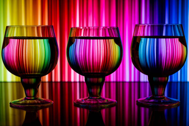 Three glasses with water on a background of colorful wallpaper reflected in the glasses