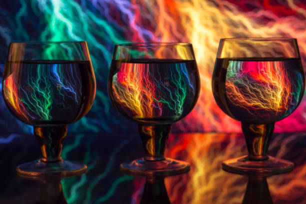 three glasses with water on the background of colorful wallpaper with the image of lightning reflected in the glass