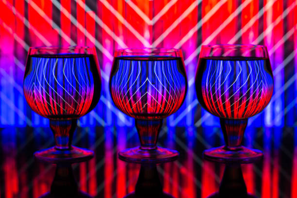 Three glasses with water on a background of wallpaper with two colors: red and blue reflected in the glasses
