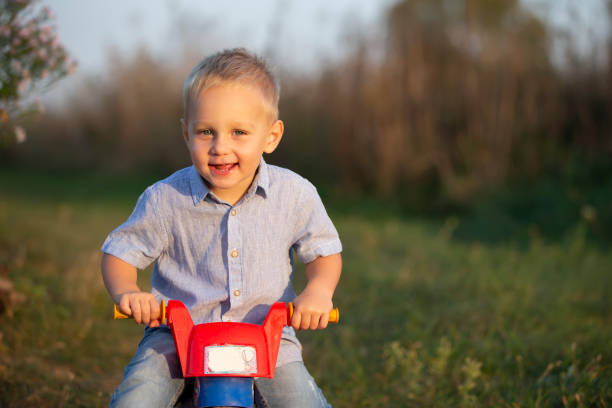istock Happy little boy rides a red toy motorcycle. 1288641337