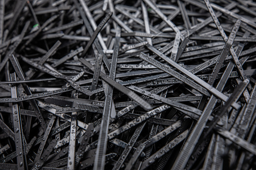 Heap of black plastic zip cable ties in recycling center, close up