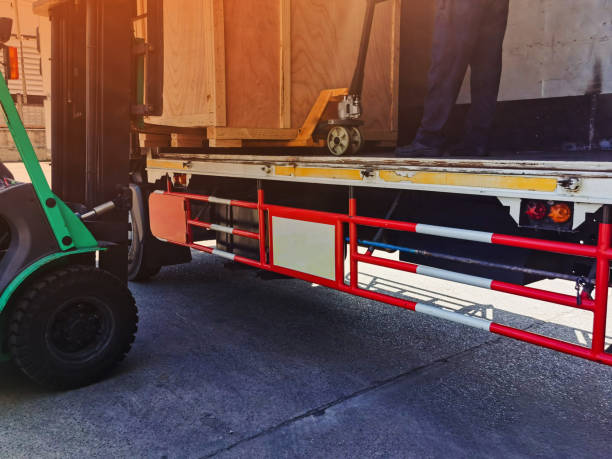 istock Worker driving forklift loading shipment carton boxes goods on wooden pallet at loading dock from container truck to warehouse cargo storage in freight logistics, transportation industrial, delivery 1288643363