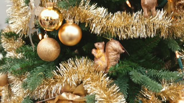 Gold color trend in Xmas tree decorations. Bulbs, tinsel, golden flowers, animal