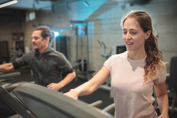 istock Focused young couple jogging on treadmills in gym 1288648149