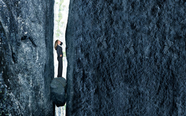 Stuck Between A Rock And A Hard Place A businesswoman stands with a look of concern as she is trapped between a rock and a hard place. trapped stock pictures, royalty-free photos & images