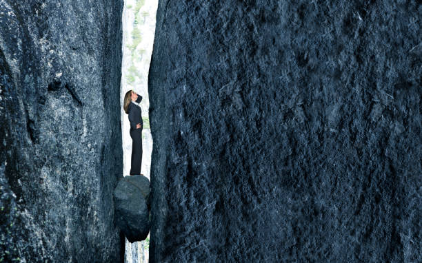 Stuck Between A Rock And A Hard Place A businesswoman stands with a look of concern as she is trapped between a rock and a hard place. stuck stock pictures, royalty-free photos & images