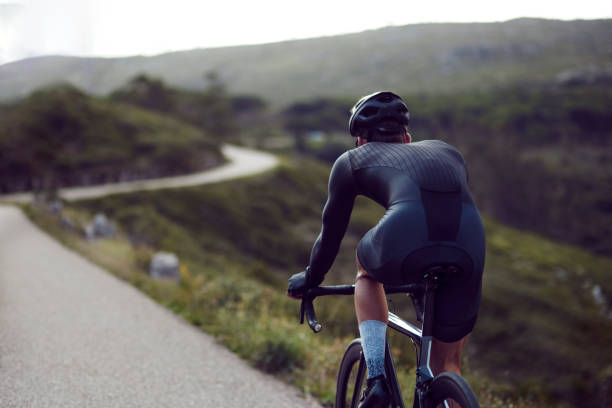 Back-view of professional cyclist riding sports bike down a mountain asphalt road