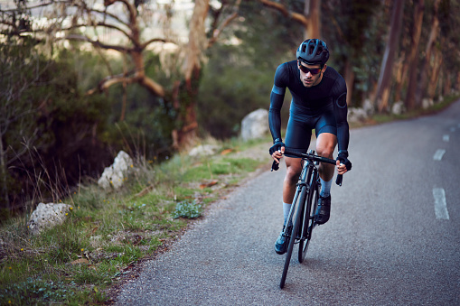 Active professional cyclist riding sports bicycle downhill on a forest