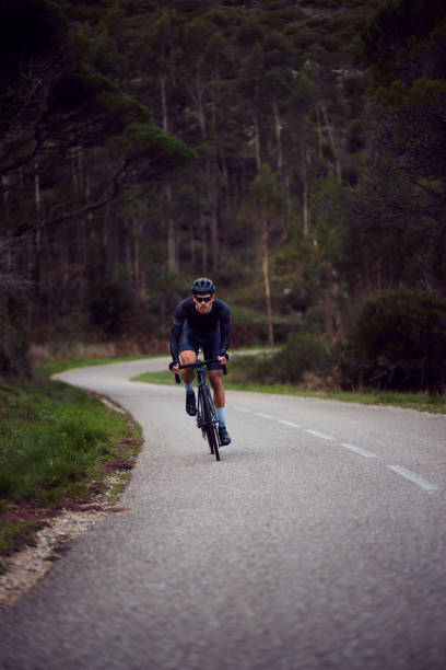 istock Professional cyclist riding bicycle climbing mountain hillside at sunrise 1288654333