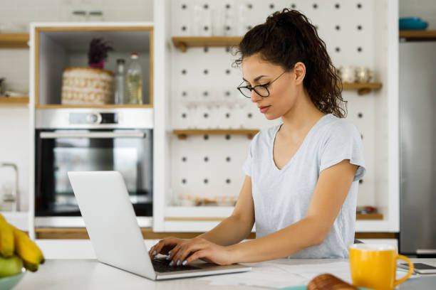 istock Woman working at home and using laptop computer in the kitchen 1288655012