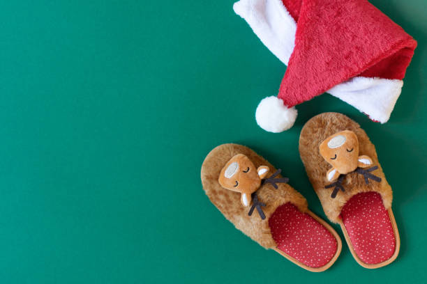 istock Cozy Christmas slippers on modern green background top view. 1288655659
