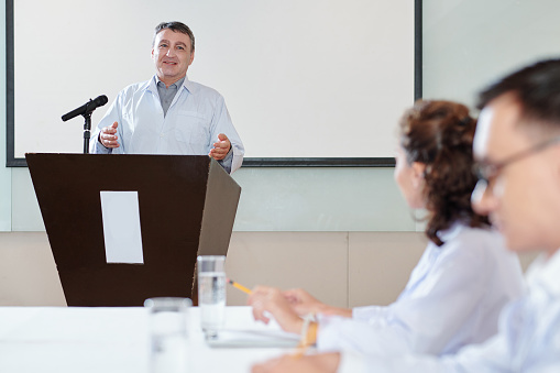 Happy mid adult leader talking to his colleagues during a business presentation in a board room.