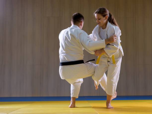 young judo girl throwing larger male opponent with leg technique - obi sash fotos imagens e fotografias de stock