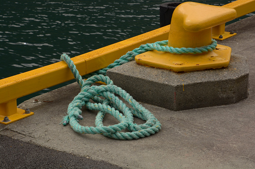 Rope tied ship on background of red ship side. Ropes hanging from fishing ship or yacht, close up.