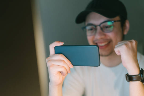 istock asian young man excited playing mobile game on his smartphone 1288661855