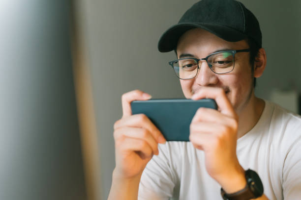 asian young man excited playing mobile game on his smartphone stock photo