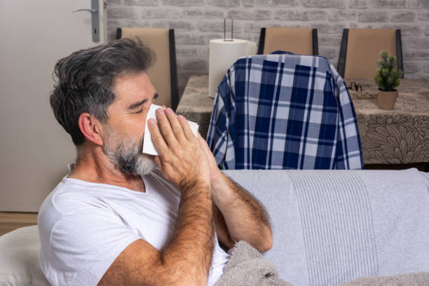 istock Man blowing his nose while lying sick in bed 1288662634