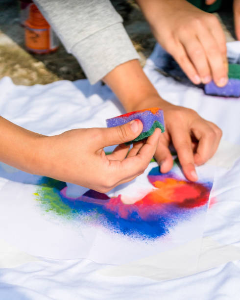 istock Creating your own t-shirt workshop outside. Hand applying paint on shirt 1288663236