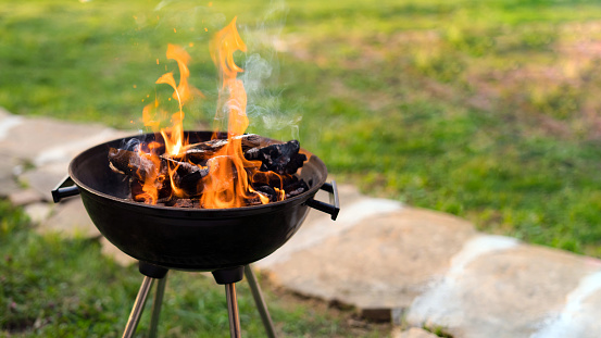 summer time in backyard garden with grill BBQ, wooden table, blurred background