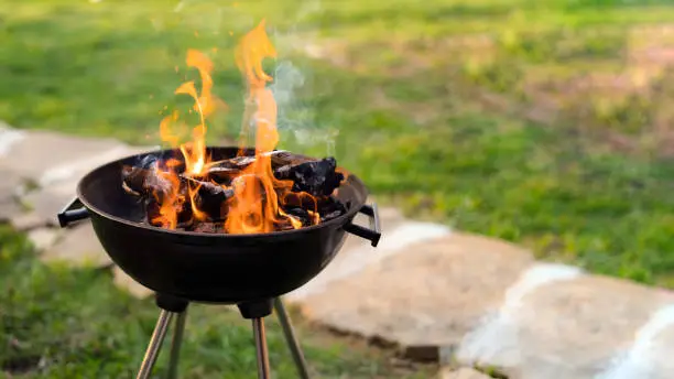 Photo of Burning wood in barbeque grill, preparing hot coals for grilling meat in the back yard. Shallow depth of field