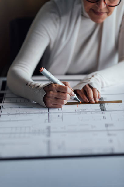 istock Anonymous Mature Architect Drawing a Plan for a New Project in her Home Office 1288664637