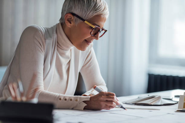 istock Beautiful Mature Architect Drawing a Plan for a New Project in her Home Office 1288664640