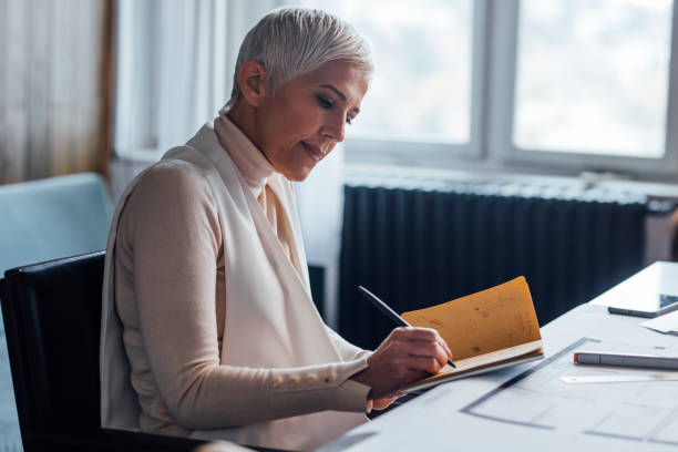 istock Beautiful Elegant Senior Architect Sketching Out the Plan for a New Project 1288664651