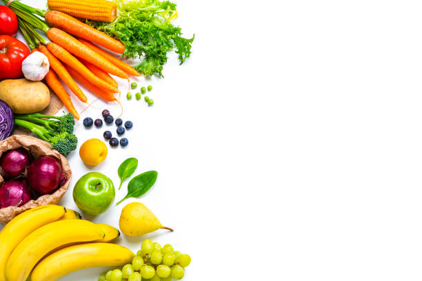 Fresh fruits and vegetables frame on white background. Copy space Food backgrounds: overhead view of healthy fresh organic multicolored fruits and vegetables arranged at the left border of a white background making a frame and leaving useful copy space for text and/or logo at the right. The composition includes carrots, tomato, corn, spinach, green peas, Spanish onion, lettuce, broccoli, radish, cabbage, potato, garlic, banana, green apple, pear, grape, blueberries and peach. High resolution 42Mp outdoors digital capture taken with SONY A7rII and Zeiss Batis 25mm F2.0 lens freshness stock pictures, royalty-free photos & images