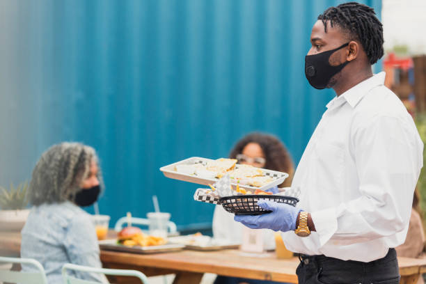 istock Waiter, wearing protective mask and gloves, serves food 1288665598
