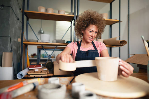 istock Female potter using adhesive tape on a flowerpot in her pottery studio 1288667078