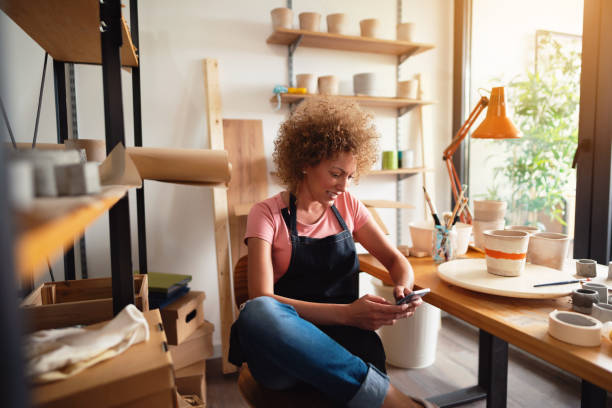 istock Smiling middle age woman texting a message in her local business pottery studio 1288667146