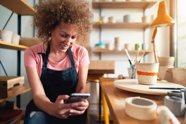 istock Female potter taking orders on smartphone in her local business pottery studio 1288667154
