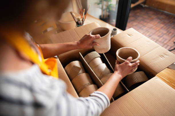 empresaria irreconocible que empaca macetas en una caja de cartón - green box fotografías e imágenes de stock