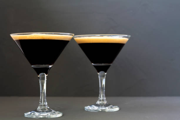 istock Espresso Martini cocktail garnished with coffee beans on dark table. Two Martini glasses on a black background. alcohol drinks. copy space. 1288667432