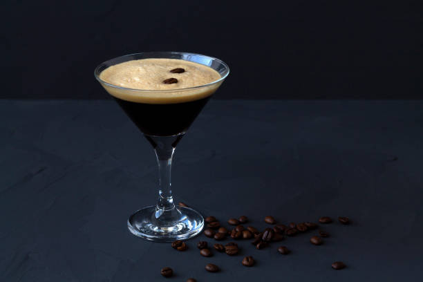 cocktail espresso martini guarnito con chicchi di caffè su tavola scura. vetro martini su sfondo nero. bevande alcoliche. spazio di copia. - luxury milk dinner glass foto e immagini stock