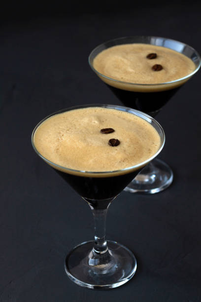 istock Espresso Martini cocktail garnished with coffee beans on table. Two Martini glasses on a black background. alcohol drinks. copy space. vertical 1288667445