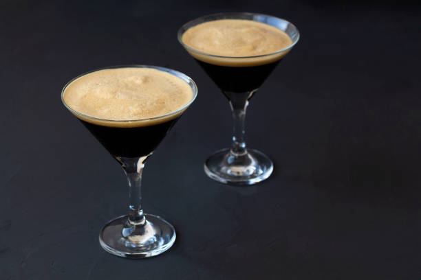 istock Espresso Martini cocktail garnished with coffee beans on dark table. Two martini glasses on a black background. alcohol drinks. copy space. top view 1288667464