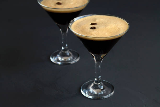 istock Espresso Martini cocktail garnished with coffee beans on dark table. Two martini glasses on a black background. alcohol drinks. copy space. 1288667467