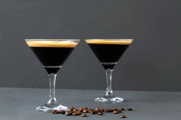 istock Espresso Martini cocktail garnished with coffee beans on dark table. Two martini glasses on a black background. alcohol drinks. copy space. 1288667470