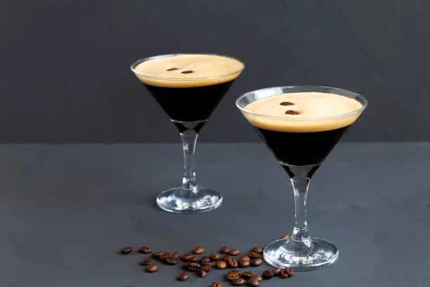 Espresso Martini cocktail garnished with coffee beans on dark table. Two Martini glasses on a black background. alcohol drinks. copy space.