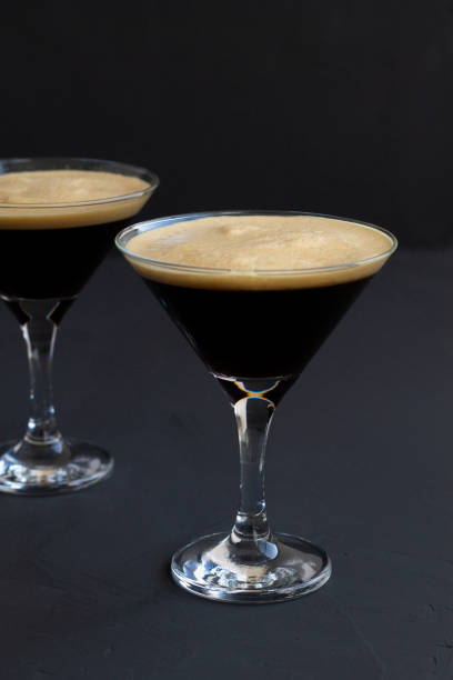 istock Espresso Martini cocktail garnished with coffee beans on dark table. Two martini glasses on a black background. alcohol drinks. copy space. vertical 1288667515