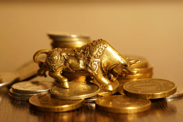istock Metal bull with coins on a gold background. 1288667754