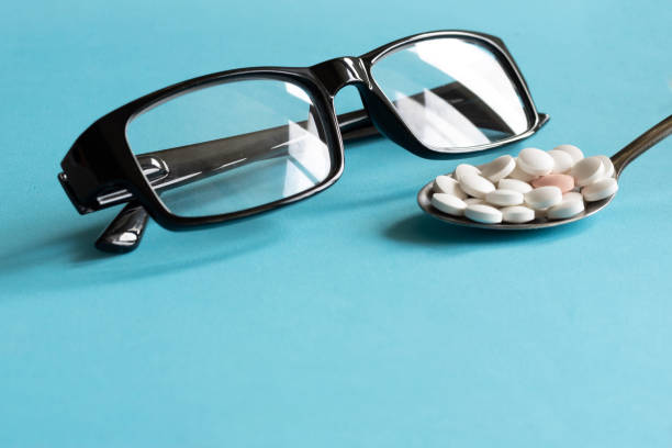 istock Glasses and pills in spoon on blue background 1288669144